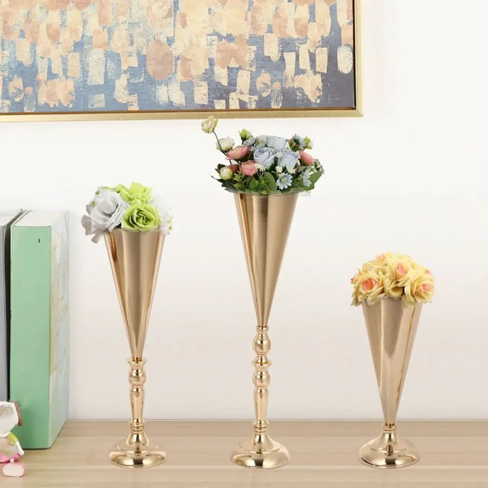 Three elegant golden silver wedding flower vases with floral arrangements on a wooden surface.