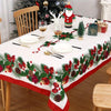 A festive red Christmas table setting featuring a green and red patterned tablecloth with holiday decorations.