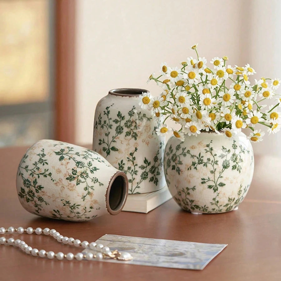 A handmade ice crackle ceramic vase with white and green floral patterns sits on a wooden surface.