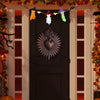 A dark wooden door decorated with Halloween-themed hanging ornaments and a large, ornate heart plaque.