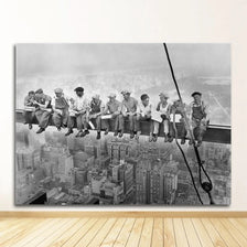 Black and white photograph of a group of men standing on a ledge overlooking a city skyline.
