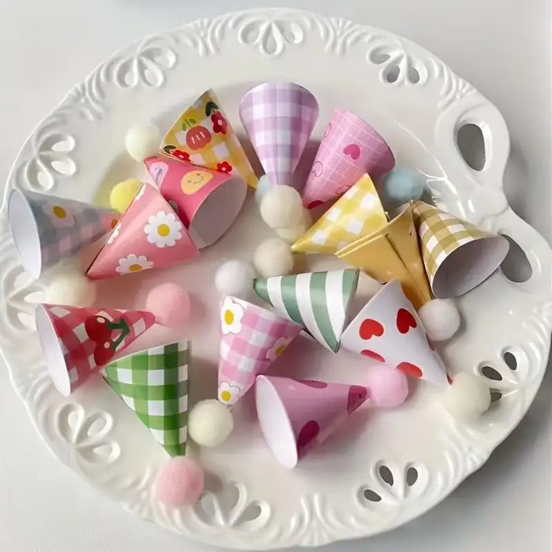 A white platter holds a collection of mini colorful party hat cake toppers in various shades of pink, yellow, and green.