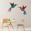 Vibrant metal hummingbird wall art featuring iridescent green, blue, and orange feathers on a light gray wall.