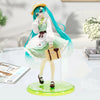 A PVC collectible figurine of Hatsune Miku in a green and white dress with long teal hair standing on a circular base.