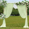 A light green chiffon backdrop curtain decorated with white flowers framing an outdoor event setting.