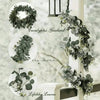 A vertical display of an artificial eucalyptus garland with white flowers, showing various arrangements and scale references.