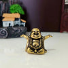 A small brass statue of a laughing Buddha with arms outstretched sitting on a white surface.