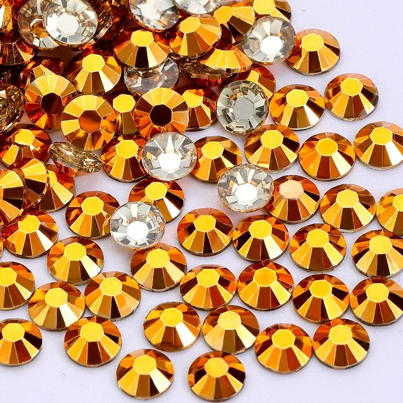 A collection of round flatback resin rhinestones in various shades of gold and clear, arranged for craft or nail art.