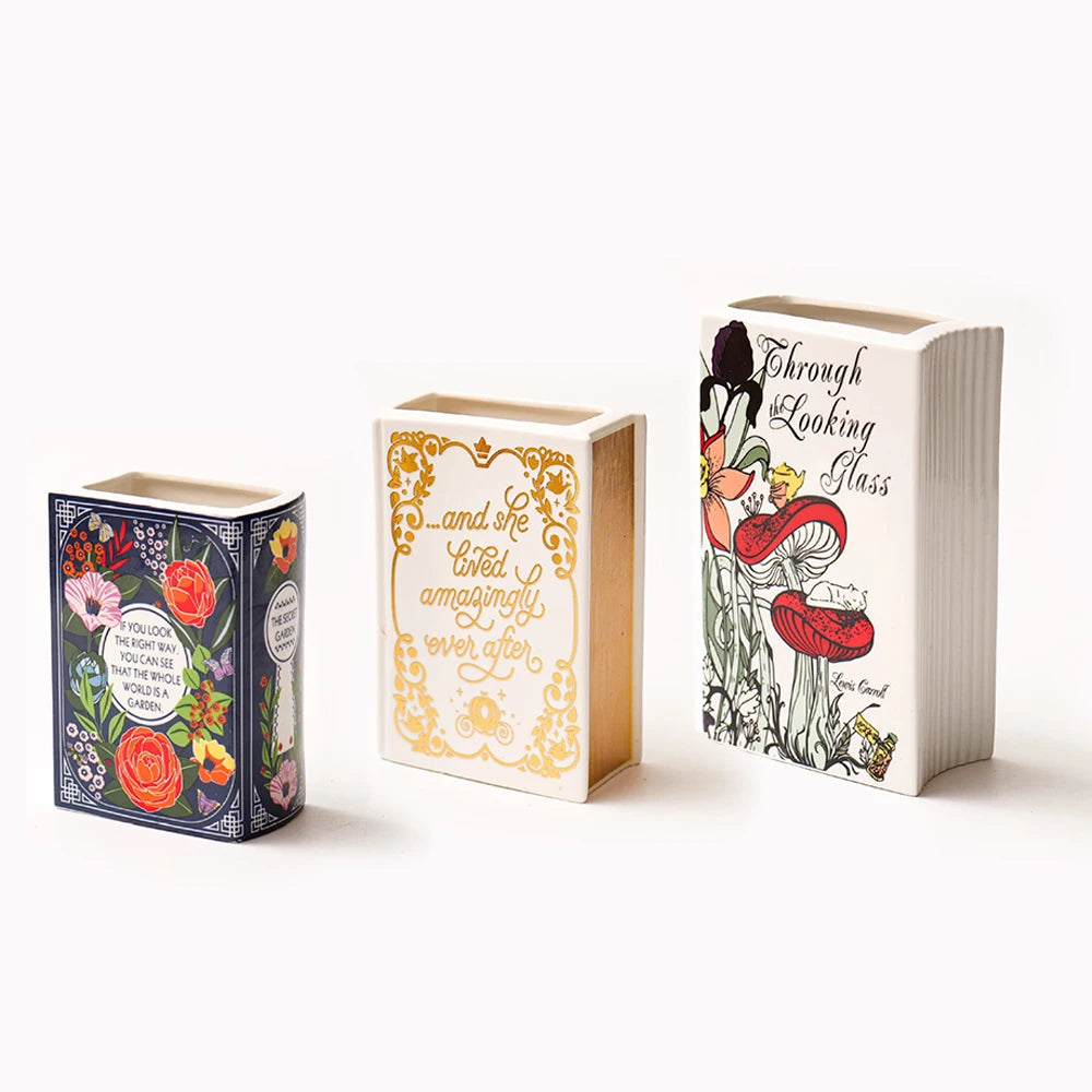 Three ceramic book-shaped vases featuring floral designs and vintage gold accents.