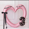 Pink heart-shaped balloon decoration with Happy Birthday text and a black ribbon.