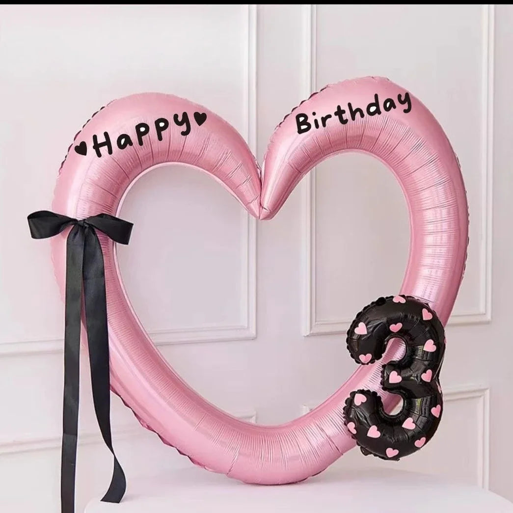Pink heart-shaped balloon decoration with Happy Birthday text and a black ribbon.