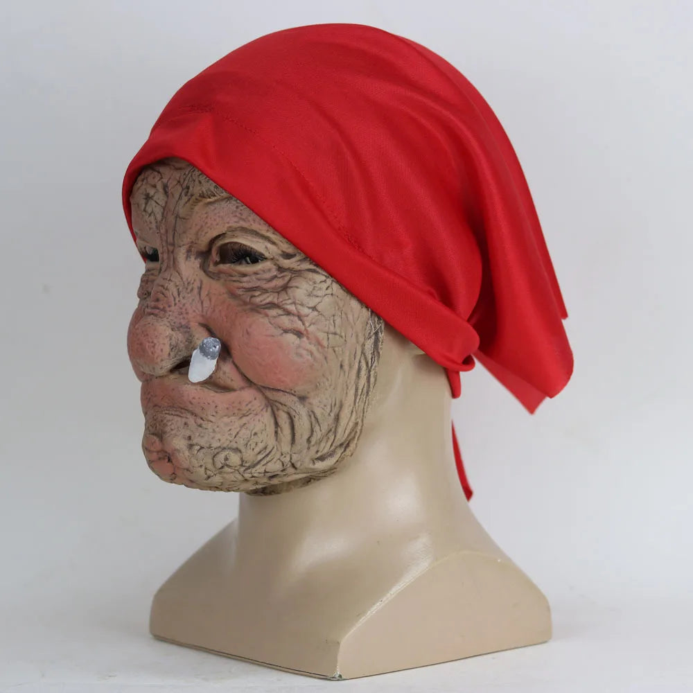 A latex mask of an elderly woman with wrinkled skin and a red scarf covering her head.