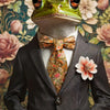 A portrait of a frog wearing a suit and tie against a floral background.