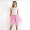 A woman models a white sleeveless top and a pink tulle tutu skirt against a white background.