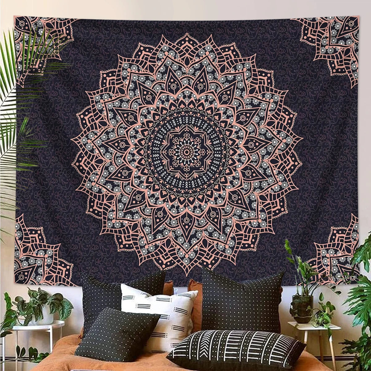 A dark tapestry wall hanging featuring a detailed mandala design in shades of pink and gray on a black background.