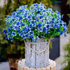 A vibrant bouquet of blue and purple silk eucalyptus and violet artificial flowers in a rustic wooden vase.