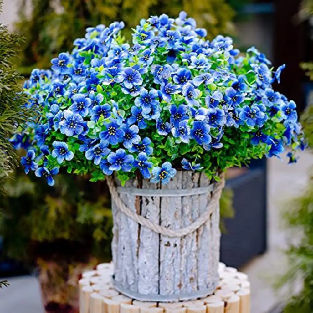 A vibrant bouquet of blue and purple silk eucalyptus and violet artificial flowers in a rustic wooden vase.