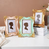 Three decorative photo frames in gold and mint green with black silhouette prints displayed on a white surface.