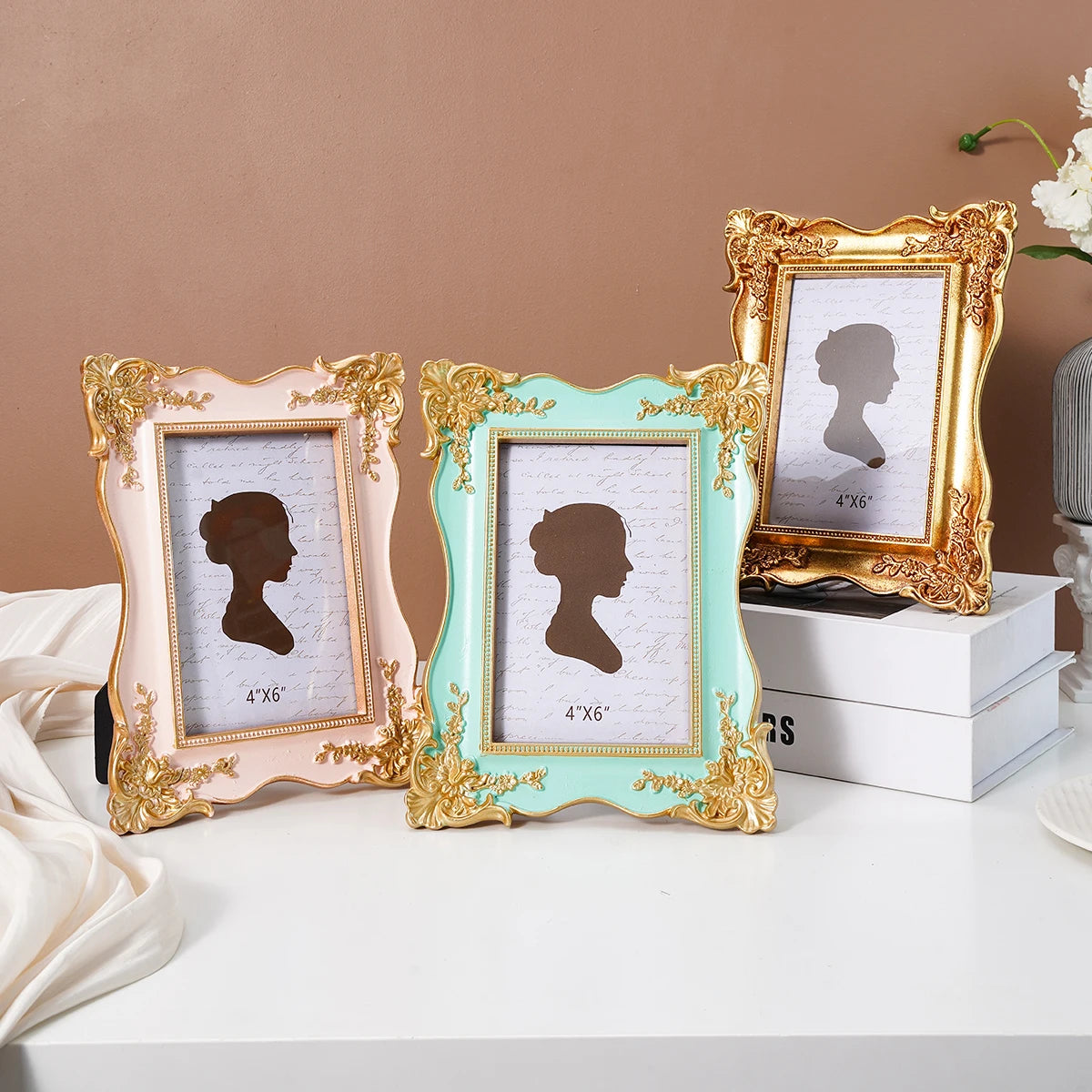Three decorative photo frames in gold and mint green with black silhouette prints displayed on a white surface.