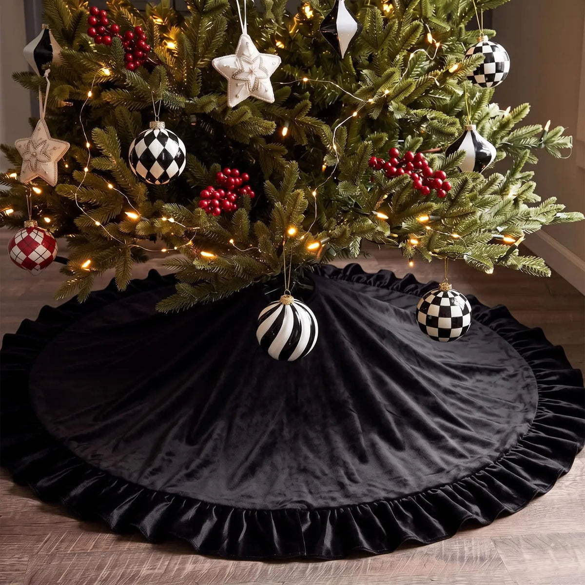 A dark velvet Christmas tree skirt decorated with silver and black geometric ornaments and a ruffled edge.