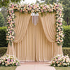 A beige satin backdrop curtain decorated with floral garlands and draped fabric for parties and photography.