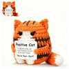 An orange and black striped crochet cat plush toy with a white belly, presented on a white background.