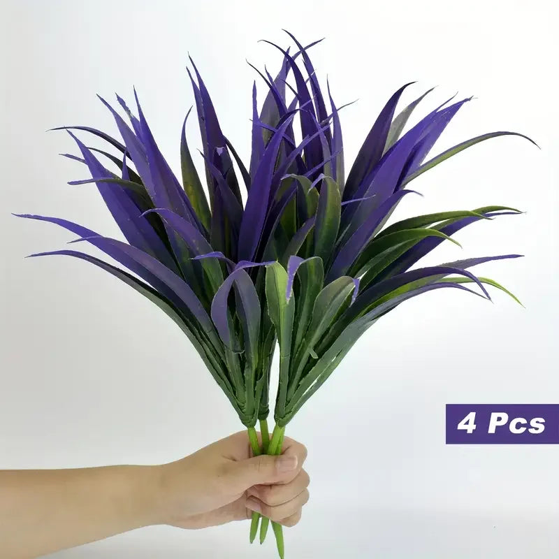 A bunch of four purple, spiky artificial tall grass and tropical flowers held in a hand.