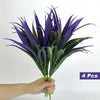 A bunch of 4 artificial tall grass and tropical flowers with deep purple blades held in a hand.