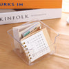 Boîte d'organisation de bureau en acrylique transparent contenant plusieurs calendriers et notes sur une surface en bois.