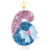 A decorative candle shaped like a donut with pink glitter and a light blue bow on top.