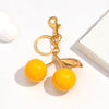 A gold-colored resin pendant keychain featuring a yellow spherical charm and a leaf design.