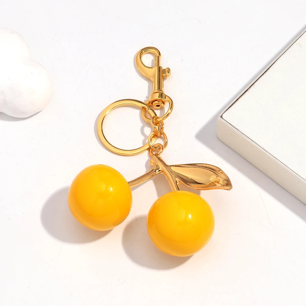 A gold-colored resin pendant keychain featuring a yellow spherical charm and a leaf design.