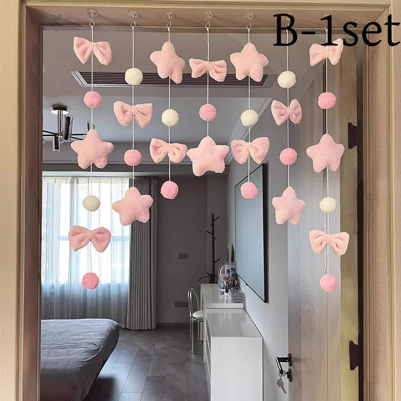 A set of pink tassel door curtains featuring heart and star decorations hanging in a doorway.