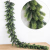 A long, green artificial pine garland hangs against a white wall, with a circular inset showing the texture of the foliage.