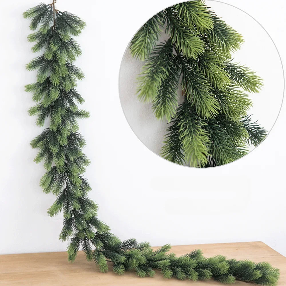 A long, green artificial pine garland hangs against a white wall, with a circular inset showing the texture of the foliage.