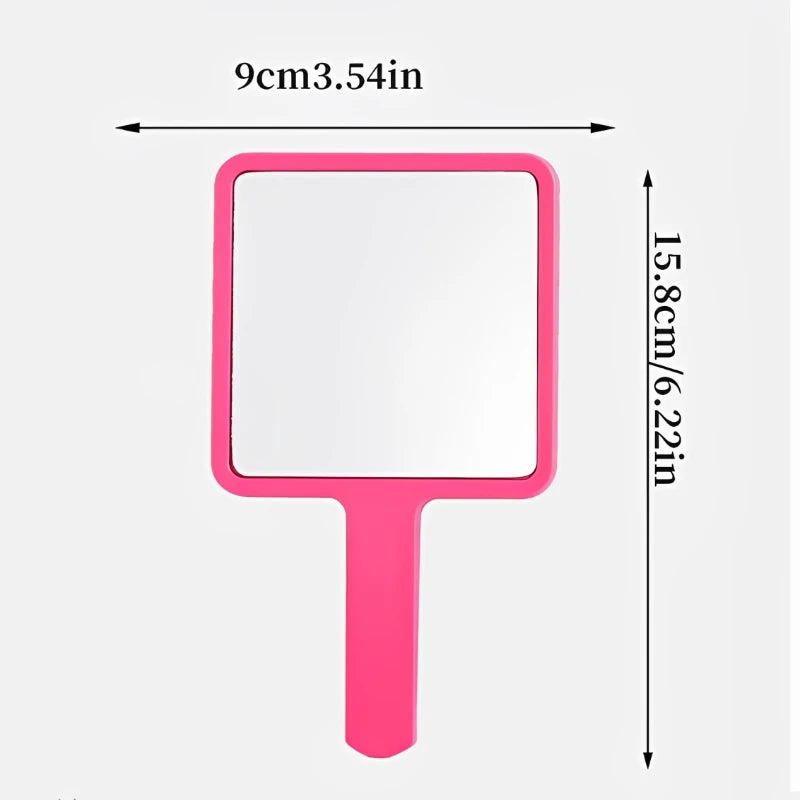 A pink handheld vanity mirror with an ergonomic handle, measuring 9cm wide and 15.8cm tall.