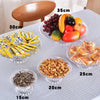 A collection of various foods including fruit, nuts, and yellow snacks displayed on clear acrylic serving plates.