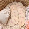 A set of wooden baby milestone cards showing 'one month' through 'five months' in pink and natural wood tones.