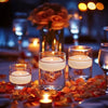 A close-up of glowing floating candles set on a table with warm lighting and autumn leaves.