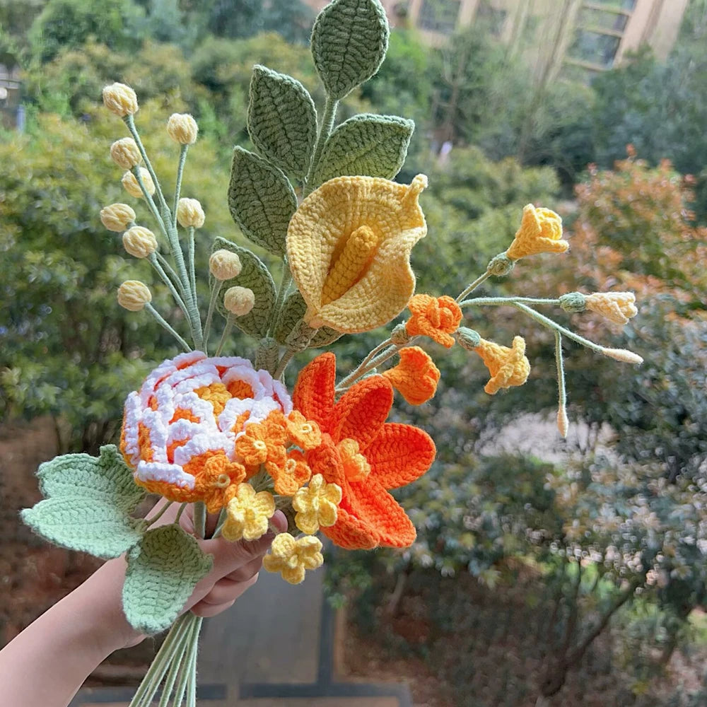 Un ramo de flores de ganchillo hechas a mano en tonos naranja, amarillo y verde contra un fondo exterior desenfocado.