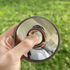 A hand holds a round convex mirror for travel and selfie props outdoors.