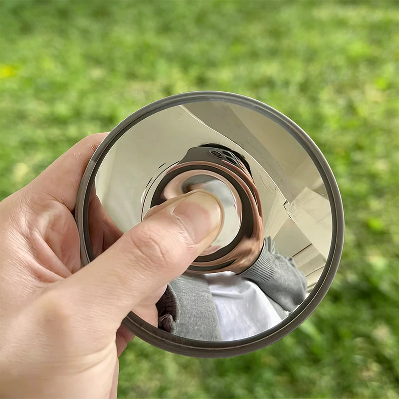 A hand holds a round convex mirror for travel and selfie props outdoors.