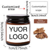A dark glass jar of ebony agarwood candle with a custom logo label and a wooden agarwood piece shown next to it.