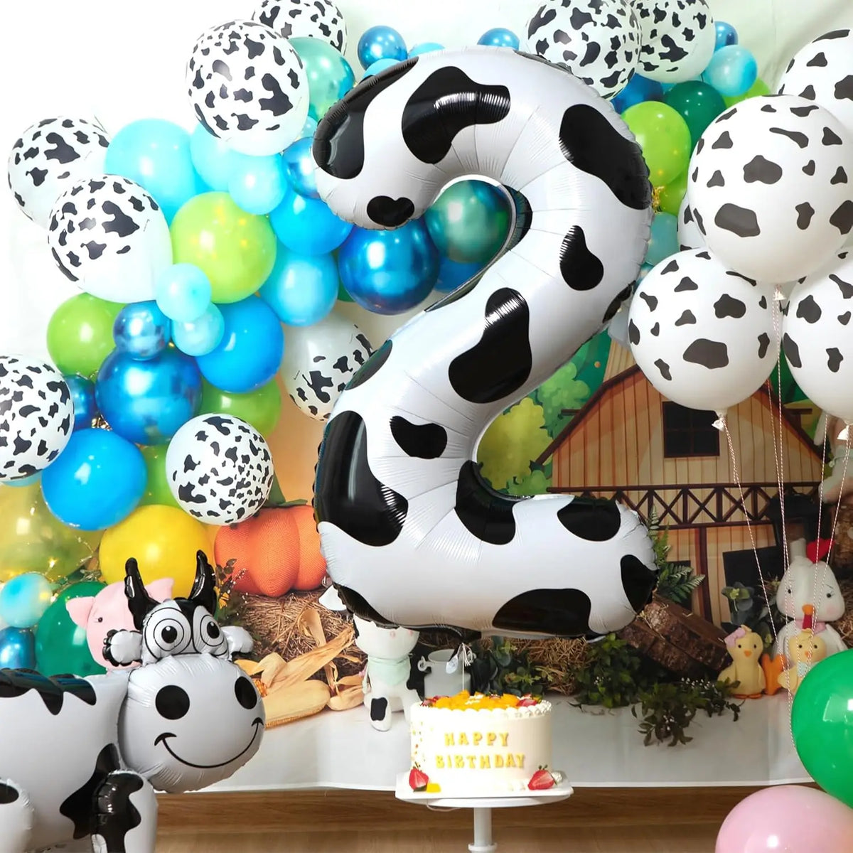 A large black and white cow print number foil balloon shaped like the number 2, used for a farm-themed birthday party decorat