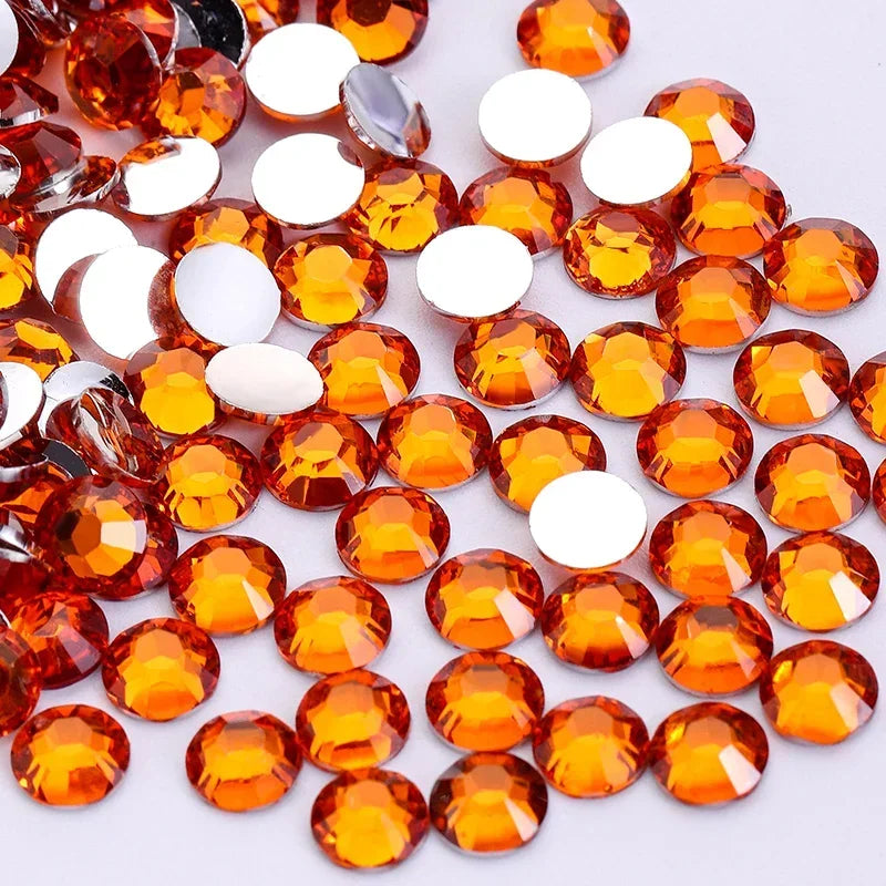 A collection of round, flatback resin rhinestones in various shades of orange and amber.