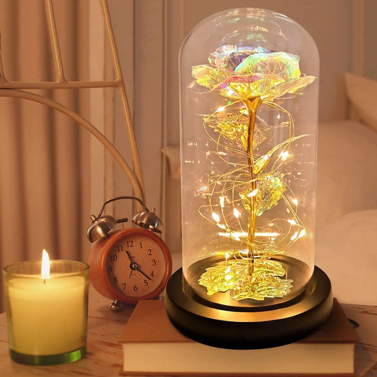 Une rose de verre éternelle avec une lumière LED est exposée sur une surface en bois à côté d'une bougie allumée.
