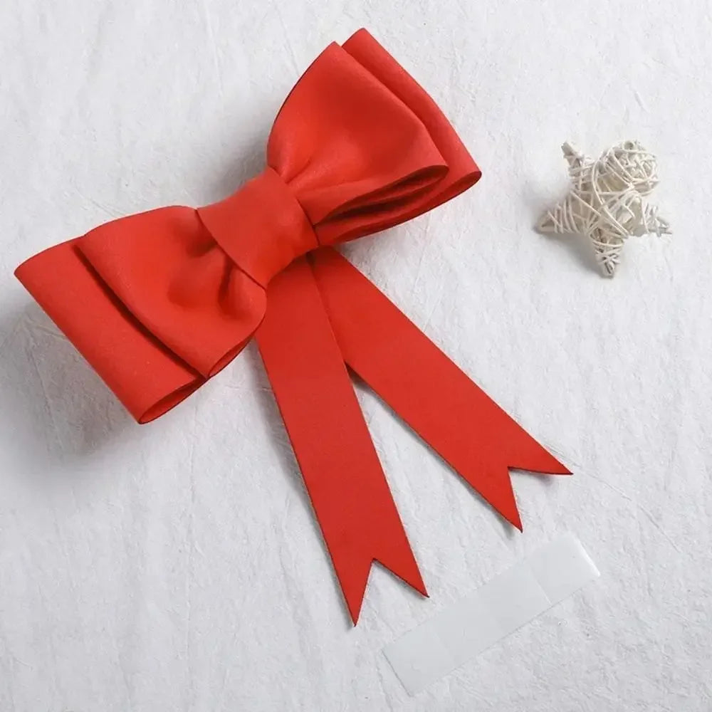 Topper de gâteau en forme de nœud décoratif rouge vif avec un ruban blanc transparent et un petit élément décoratif blanc.