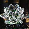 A clear crystal lotus flower ornament with green accents displayed on a dark surface.