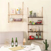 Rustic wooden hanging shelves with rope displaying various decorative items and books on a light wall.