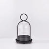 Antique brass metal candle holders with glass domes on a white surface.